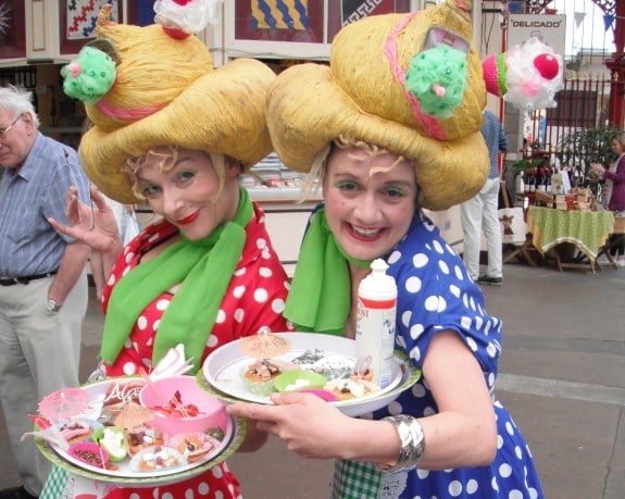 Two characters in 1950's style polka dot dresses with a selection of cakes