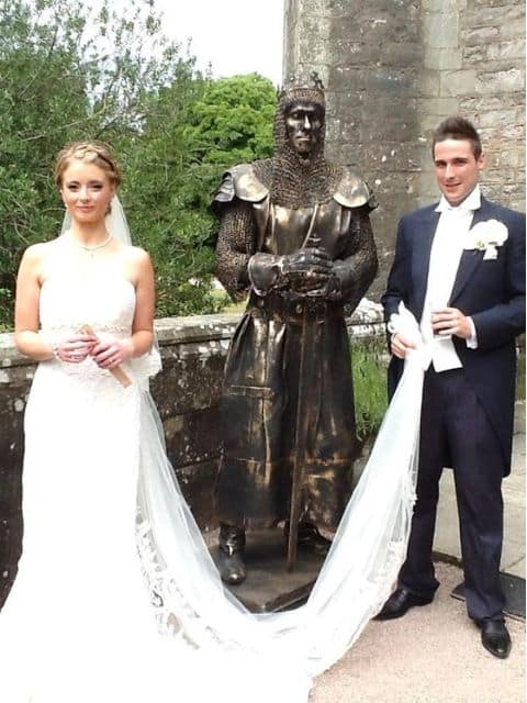 Human statue of a knight in armor stood with bride and groom